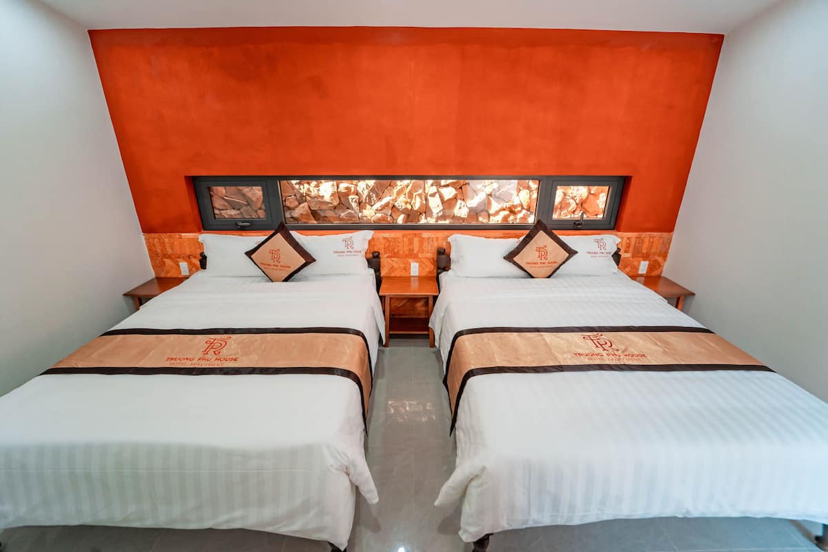 A hotel room with two beds, orange walls, and a fireplace.