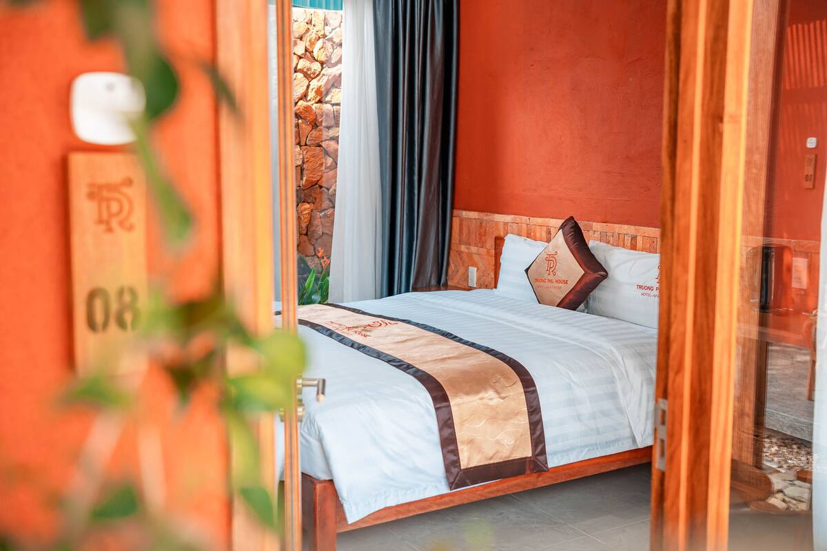 A hotel room with a bed, a stone wall, and a curtain.
