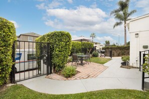 Enjoy outdoor dining on the patio surrounded by a well-maintained yard and a hedge.