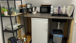 A compact kitchen with a refrigerator, microwave, coffee maker, and a small sink.