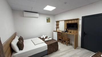 Un dormitorio con cama, escritorio, silla, televisor y puerta.