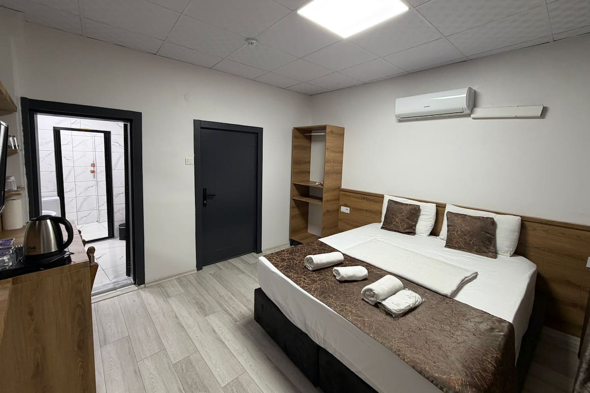 Ein modernes Hotelzimmer mit einem Bett, einem Schreibtisch, einem Kleiderschrank und einer Klimaanlage.