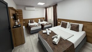 Een hotelkamer met twee bedden, een houten garderobe, een airconditioning en een televisie.