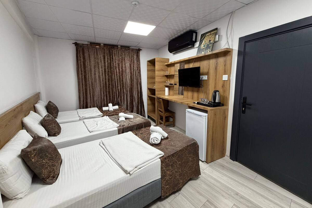 Ein Hotelzimmer mit zwei Betten, einem Schreibtisch, einem Fernseher, einer Kaffeemaschine und einem Kleiderschrank.