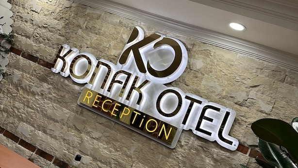 Een receptiebalie met een achtergrond van een stenen muur en een bordje met de tekst 'Konak Hotel Reception'.