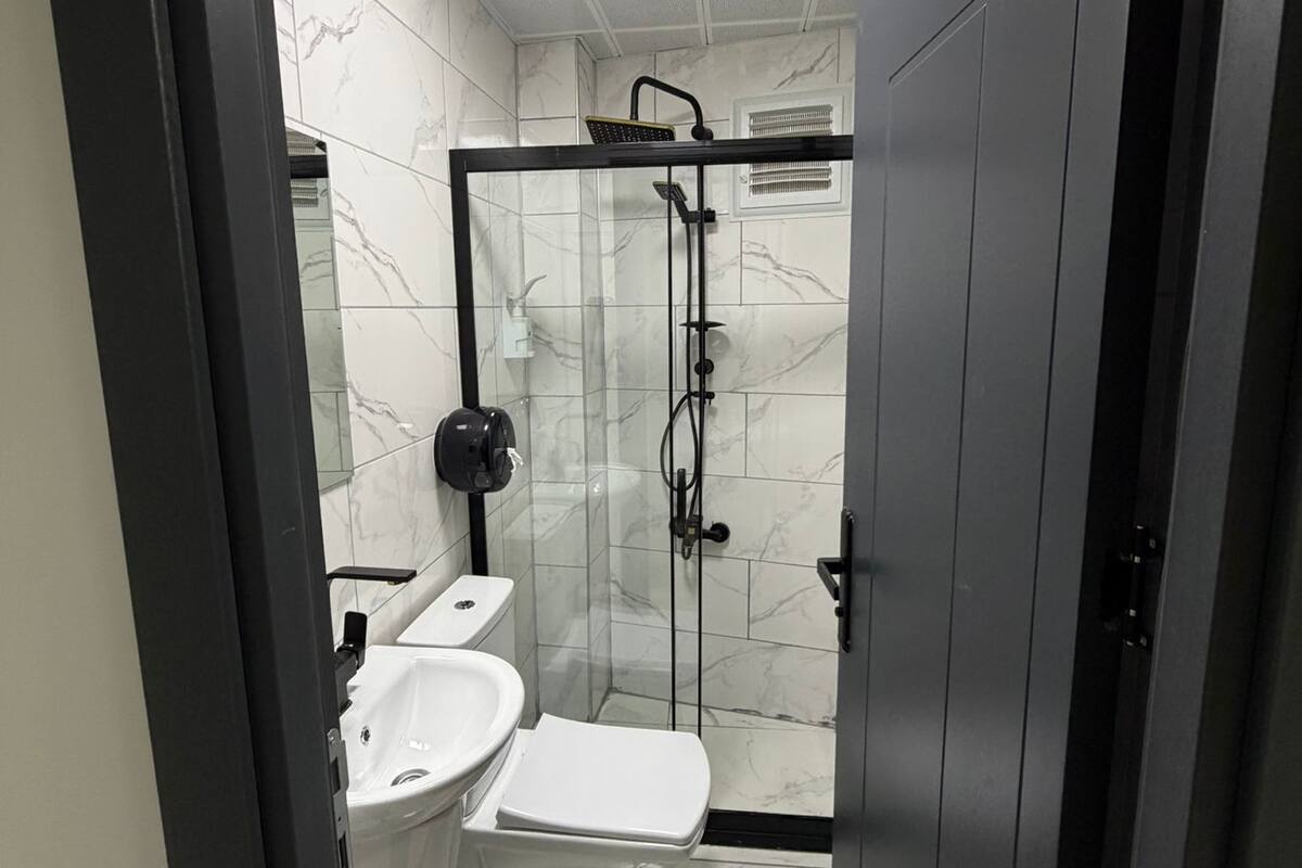 Ein modernes Badezimmer mit einer Duschkabine, einer weißen Toilette und einem Waschbecken.