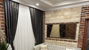 Een woonkamer met een beige bank, een ronde salontafel en een accentmuur van baksteen.