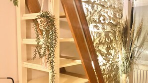 Un escalier avec une rampe en bois et un mur blanc orné d’un motif en pierre texturée.