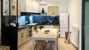 Une cuisine moderne avec des meubles en bois, une table à manger blanche et une poubelle en acier inoxydable.