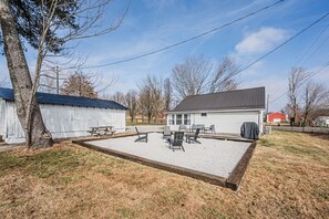 A fenced outdoor area with a picnic table and chairs, a small shed, and a house with a garage. - Mammoth Cave Getaway (Cave City)