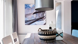A dining area with a wooden table, a woven basket, and a modern lamp. - Luxury Home by De Alde Feanen Reserve (Earnewald)