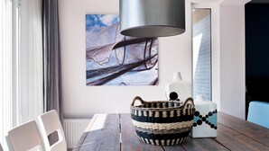 A dining area with a wooden table, a woven basket, and a modern lamp. - Bungalow near De Alde Feanen Reserve (Earnewald)