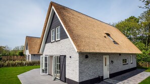 Ein modernes Haus mit geneigtem Dach, einer Ziegelaußenwand und einem gepflasterten Einfahrt.