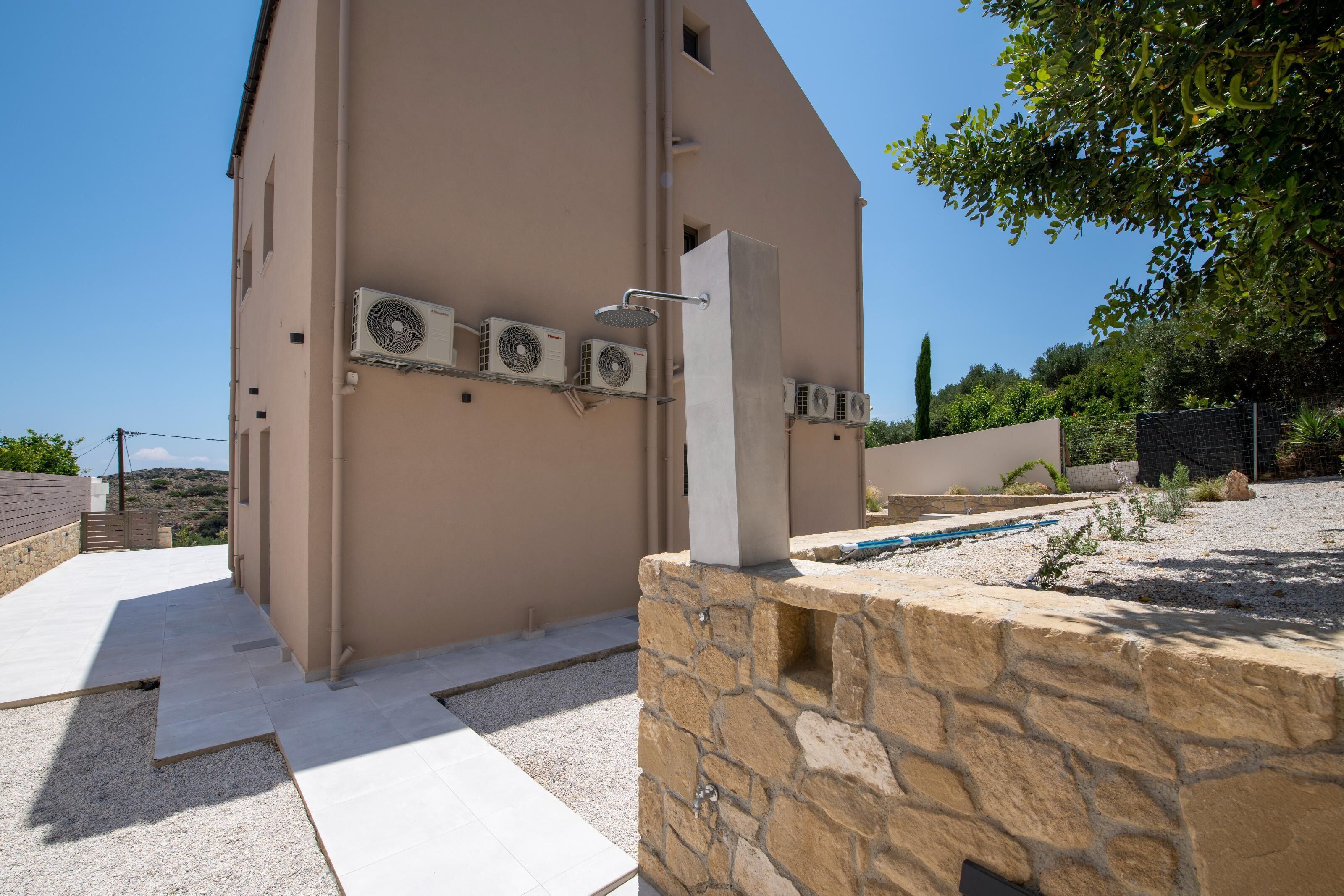 Un bâtiment doté de climatiseurs, d’un mur en pierre et d’un espace piscine.