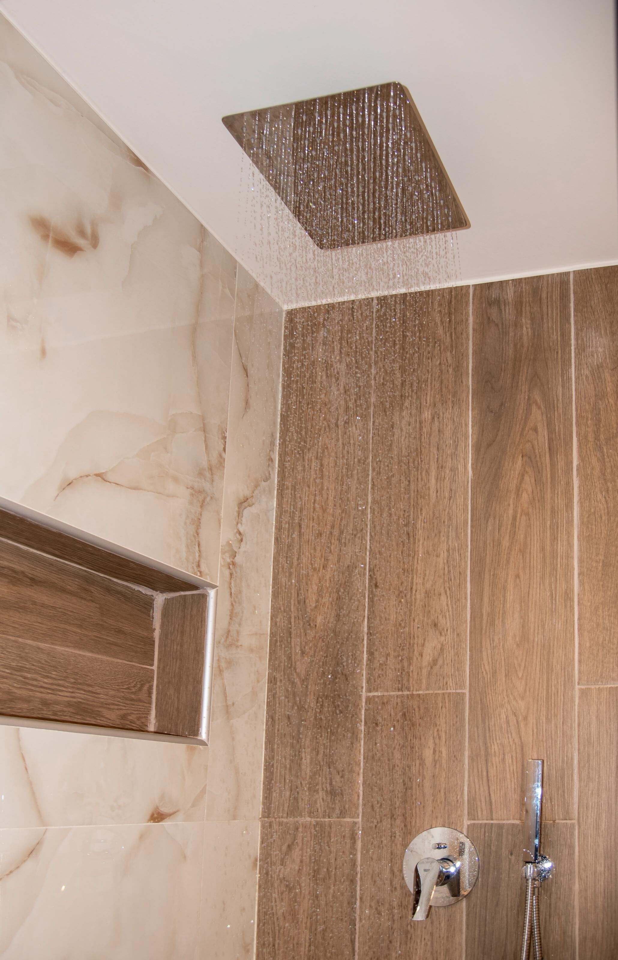 A shower with a square rainhead, a handheld showerhead, and a wall-mounted control.