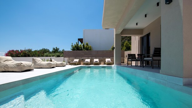 A modern outdoor pool area with lounge chairs and a dining area. - Armour Eclectic Villa (Platanias)