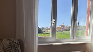 A room with a large window overlooking a town with buildings and greenery.