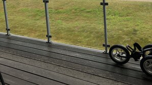Vista desde un balcón sobre un campo de golf con terraza de madera y una bicicleta.
