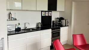 Una cocina moderna con armarios blancos, encimera negra y sillas rojas.