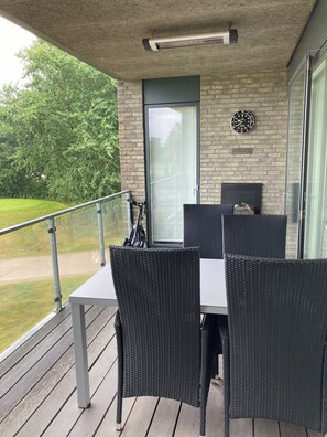 Un balcon avec des meubles en osier, une horloge et une porte.