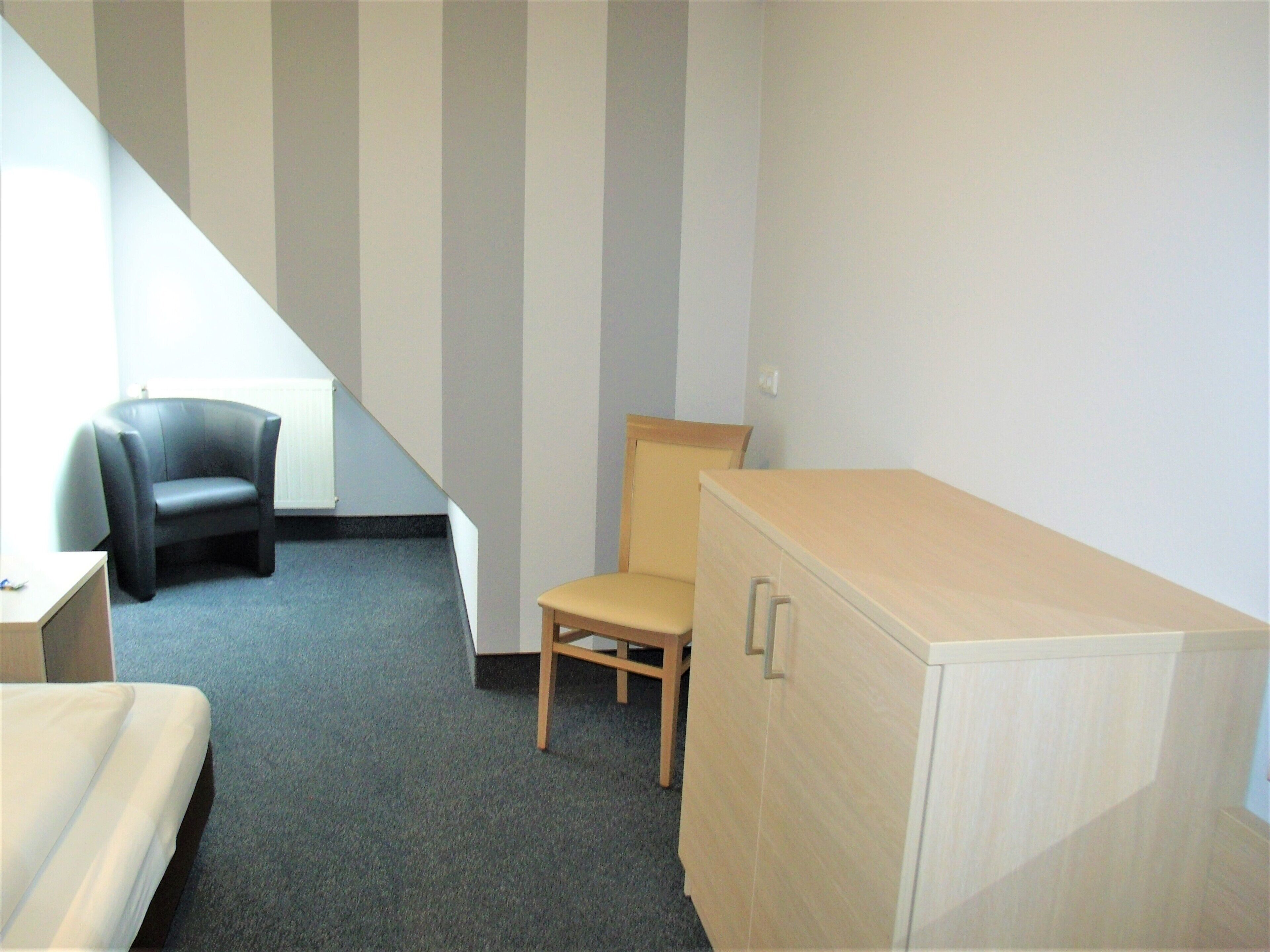 A room with a bed, a desk, a chair, and a cabinet.