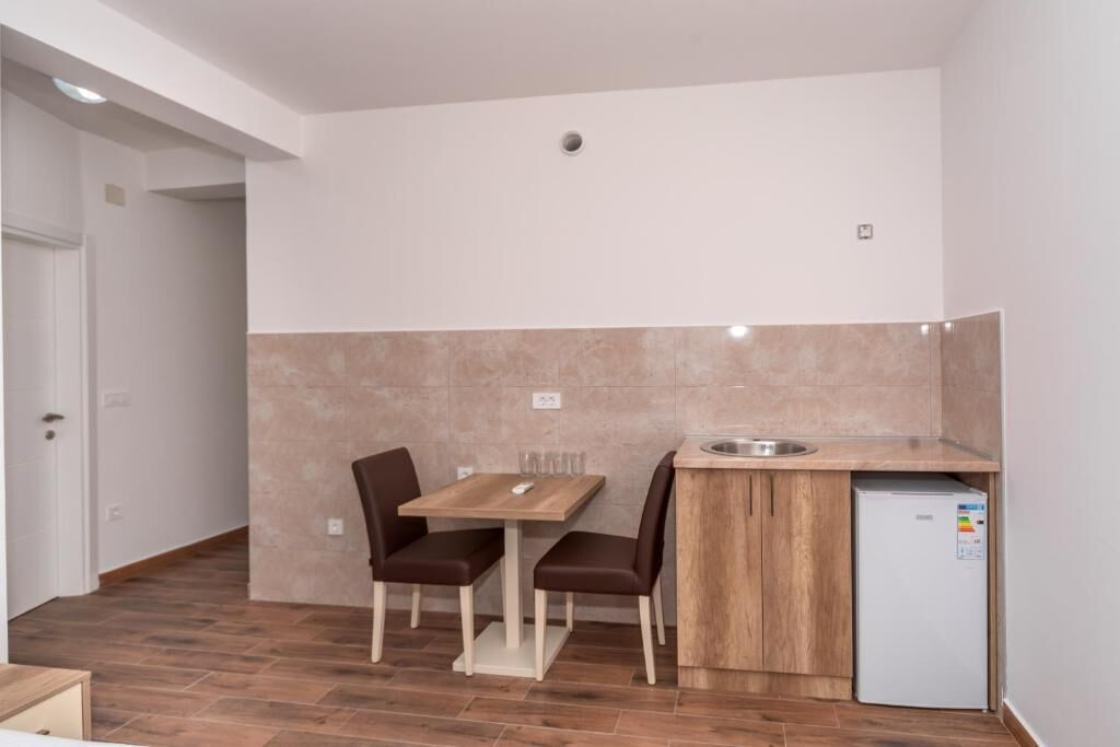 A compact kitchen with a wooden table and chairs, a built-in sink, and a white refrigerator.