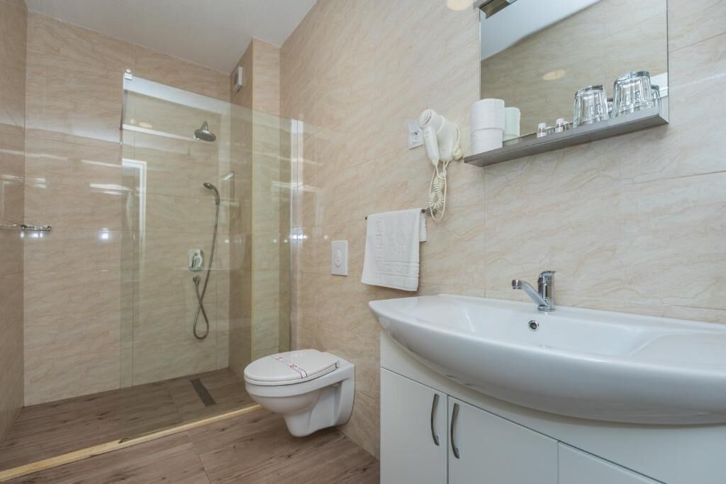 A modern bathroom with a glass-enclosed shower, a white sink, and a mirror above the sink.