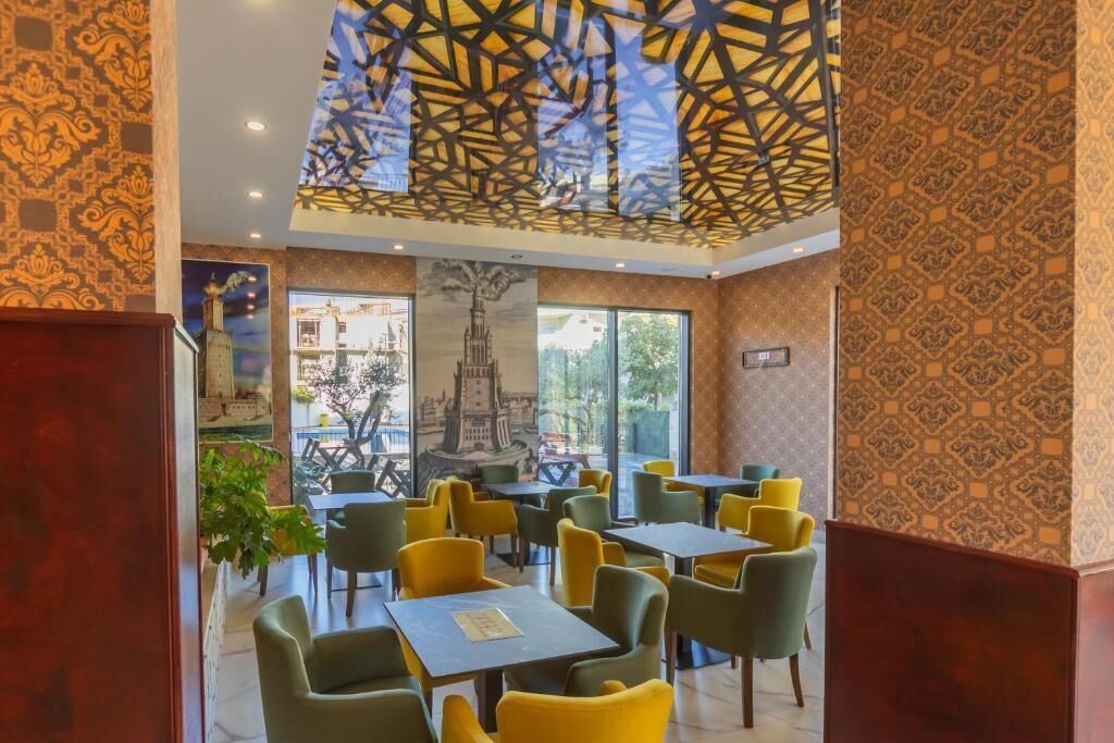 Restaurante com parede estampada, mural de paisagem urbana e design geométrico no teto.