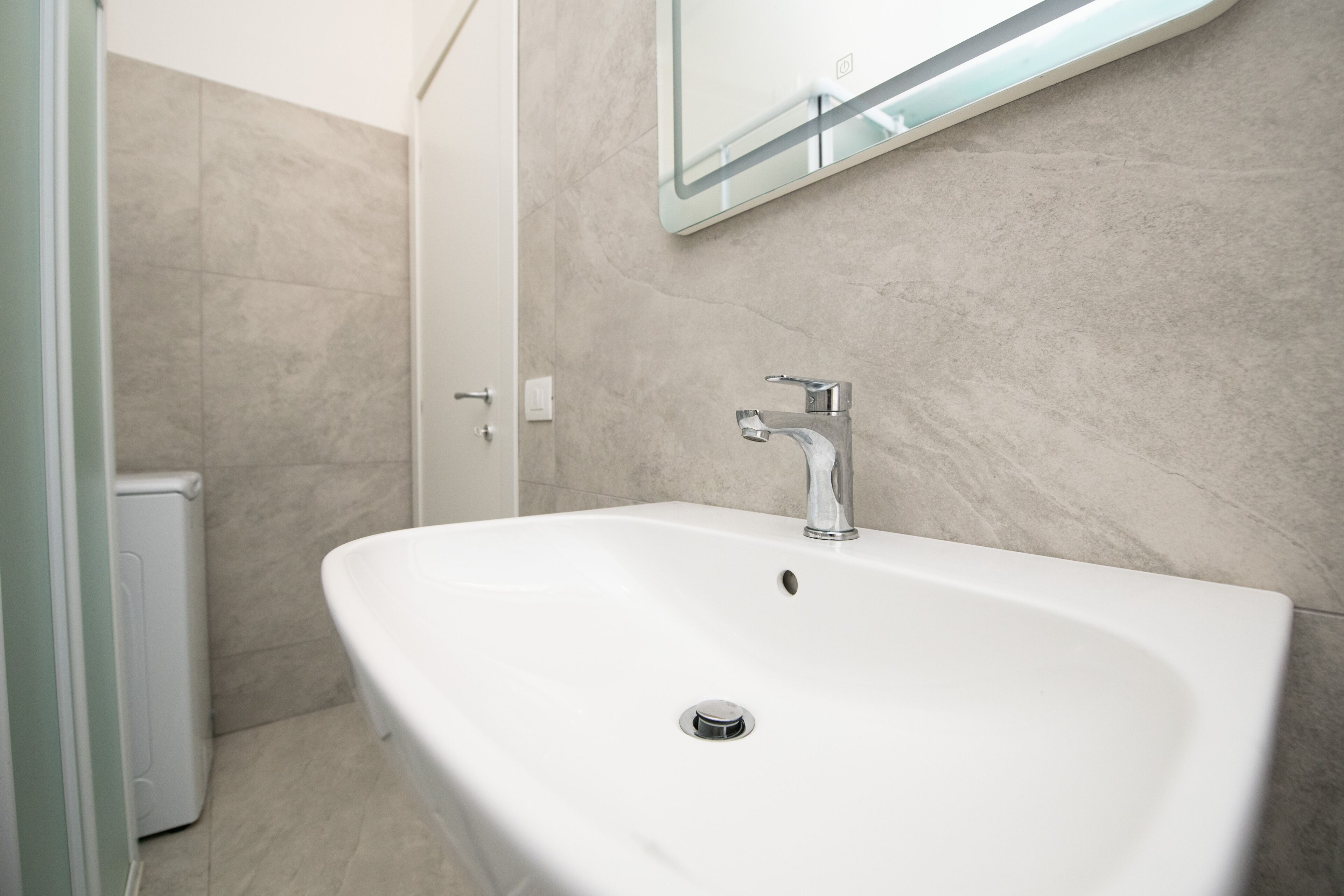 A bathroom with a white sink, a mirror, and a shower area.