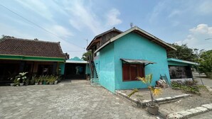 Ein Wohngebiet mit einem blauen Haus, einem Ziegeldach und einem gepflasterten Innenhof.