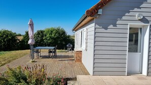 A house with a deck, a barbecue grill, and a patio umbrella. - Charming little gîte in the heart of the Baie de Somme (Saigneville)