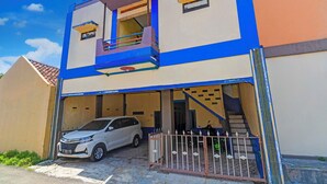 A two-story building with a white car parked in front. - Hotel O Wisma Dua Putra Syariah (Kertajati)