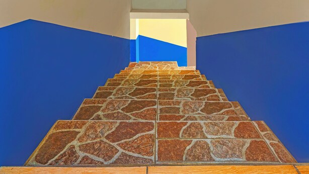 A staircase with stone steps leading upwards, surrounded by walls painted in blue and beige. - Hotel O Wisma Dua Putra Syariah (Kertajati)