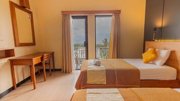 A hotel room with a desk, two beds, a balcony with a view, and a large mirror on the wall.