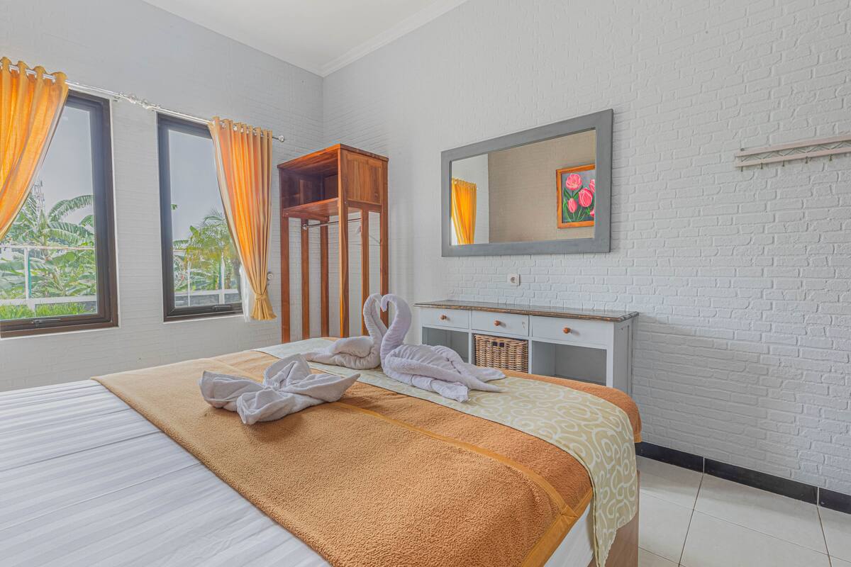 Ein Hotelzimmer mit einem Bett, einem Holzschrank, einem Spiegel und einem Fenster mit Vorhängen.