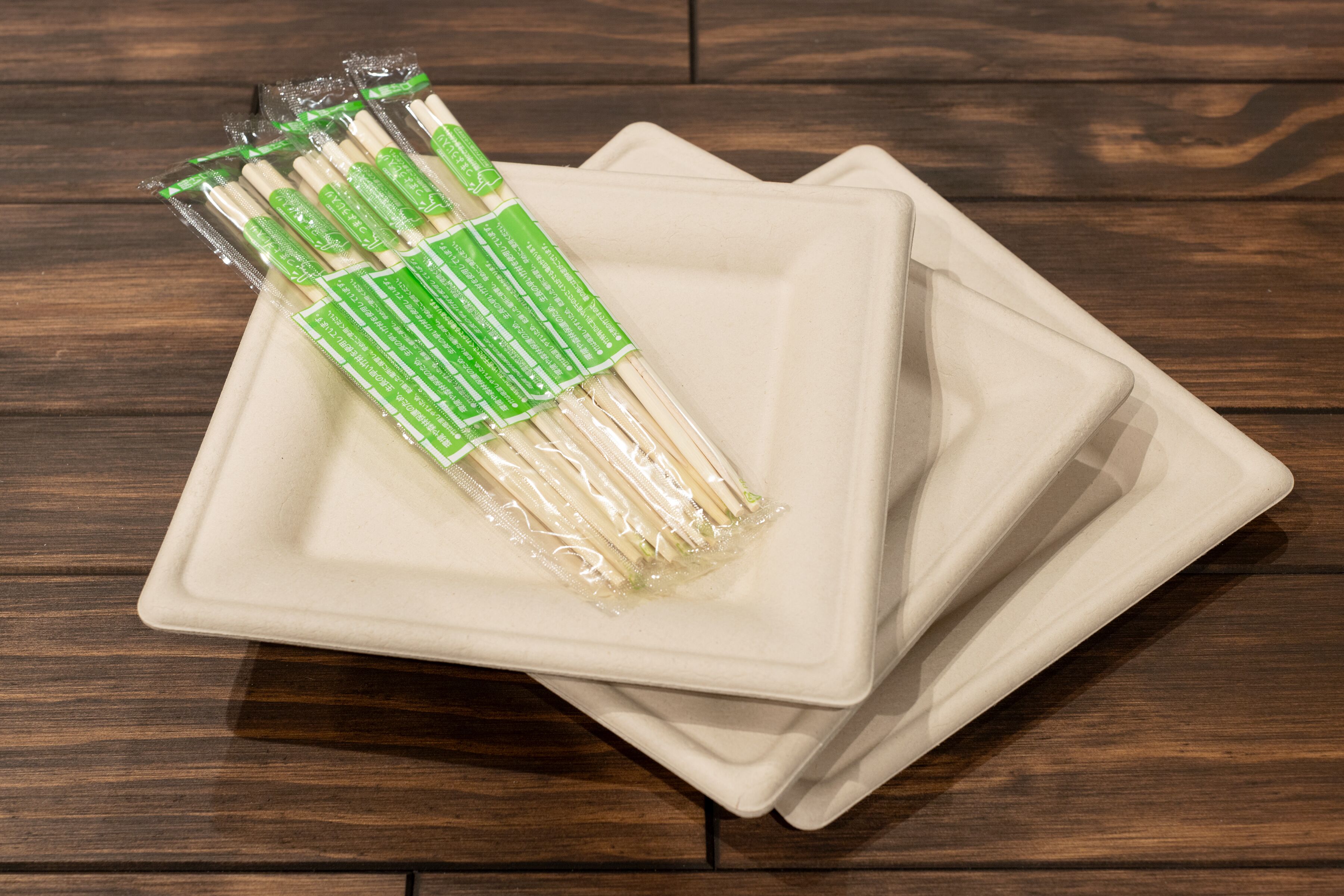 A stack of white square plates on a wooden surface.