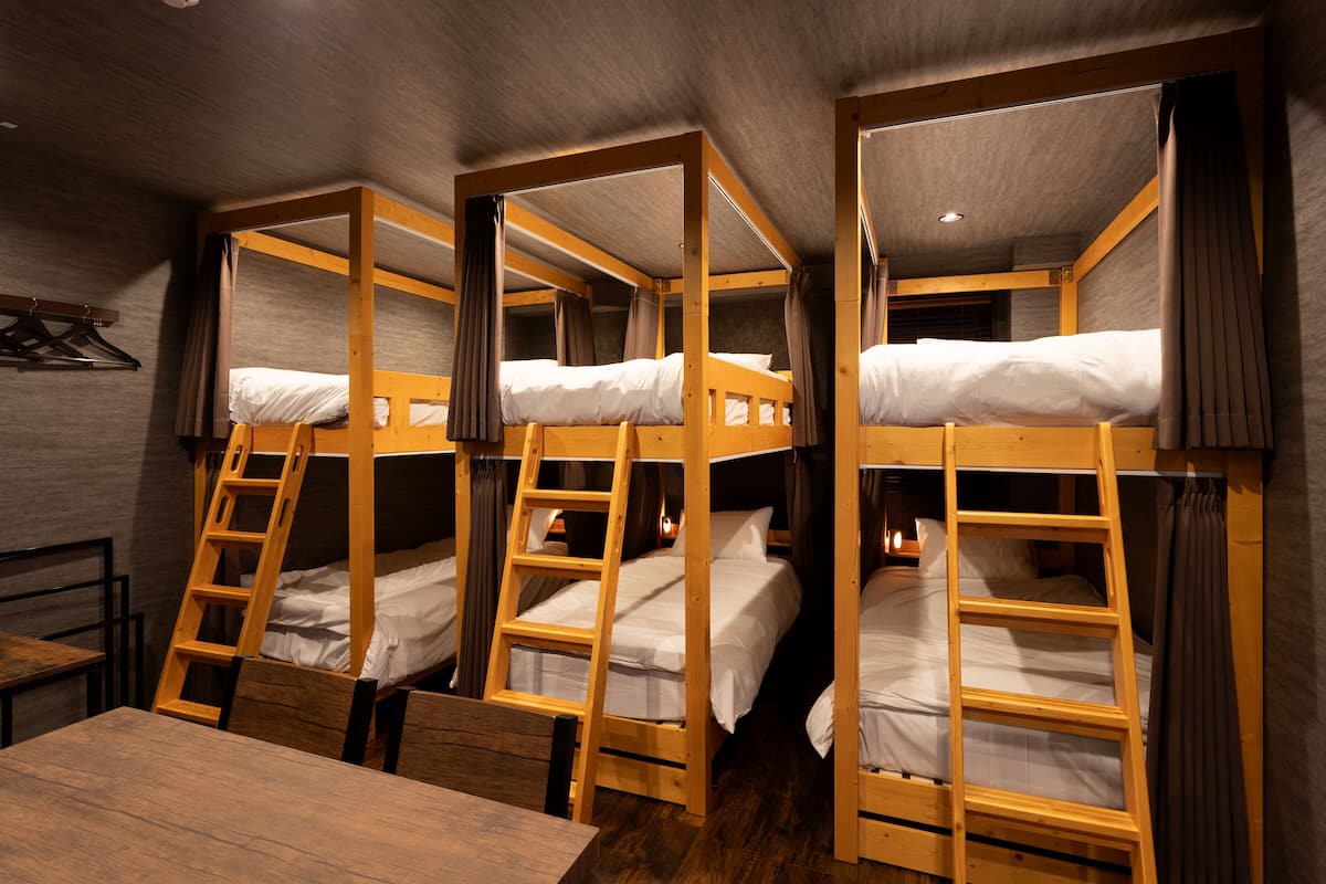 Une chambre avec un lit superposé à ossature en bois, une table en bois et un porte-manteau suspendu.