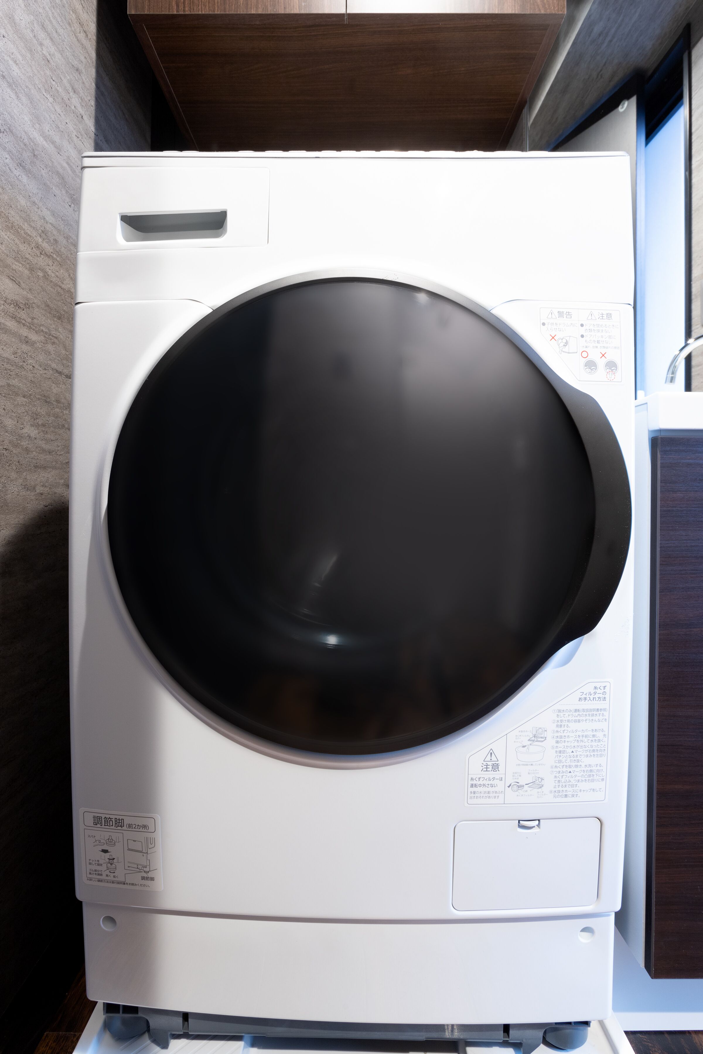 A front view of a white washing machine with a control panel and instruction manual.