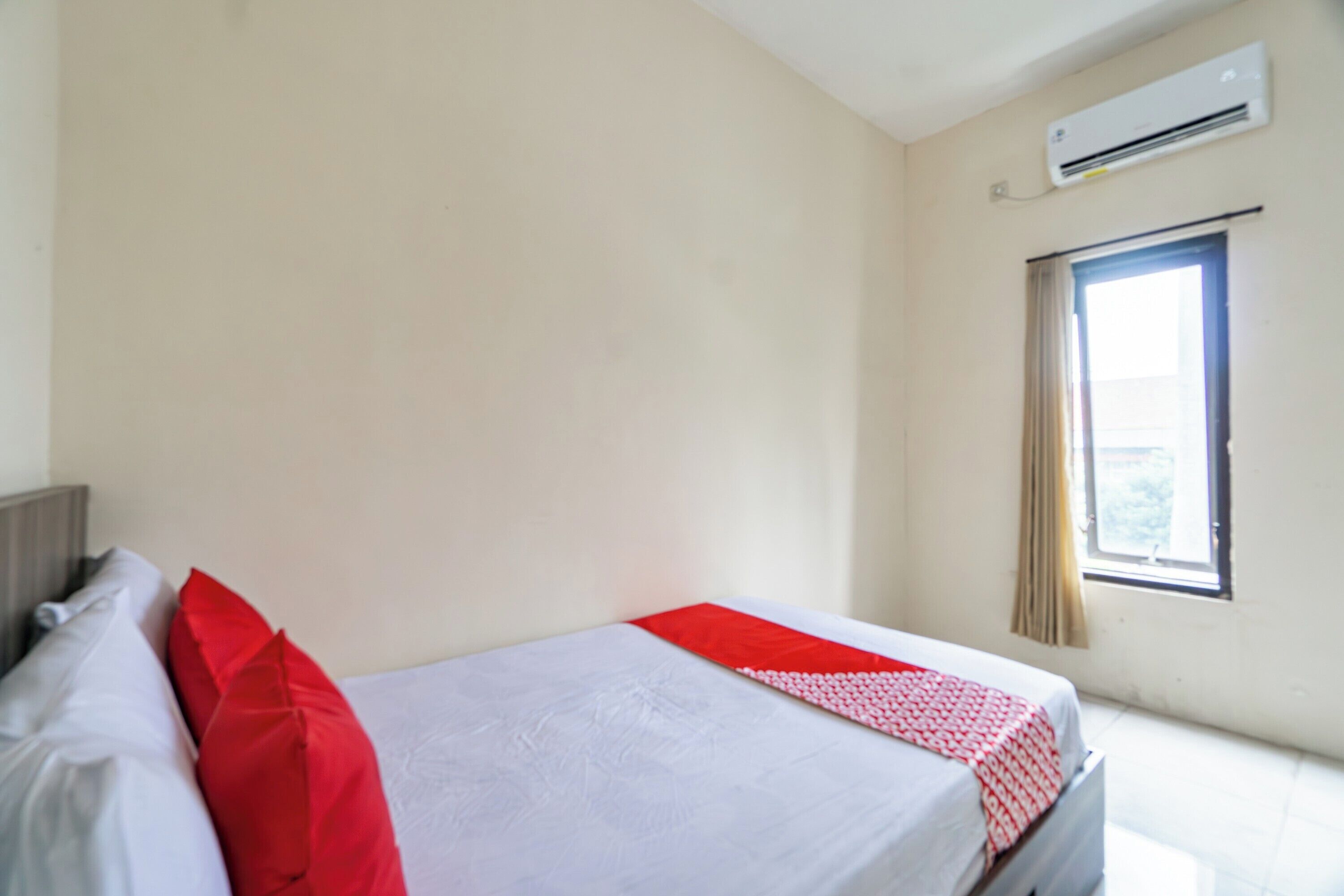 Una habitación de hotel con cama, ventana y aire acondicionado.