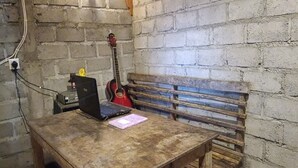 Une pièce rustique avec une table en bois, une guitare rouge et un ordinateur portable.
