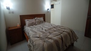 Une chambre à coucher avec un lit en bois, une table de chevet et deux lampes fixées au mur.