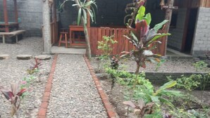 Un sentier de jardin menant à une structure en bois, avec un banc et une table.