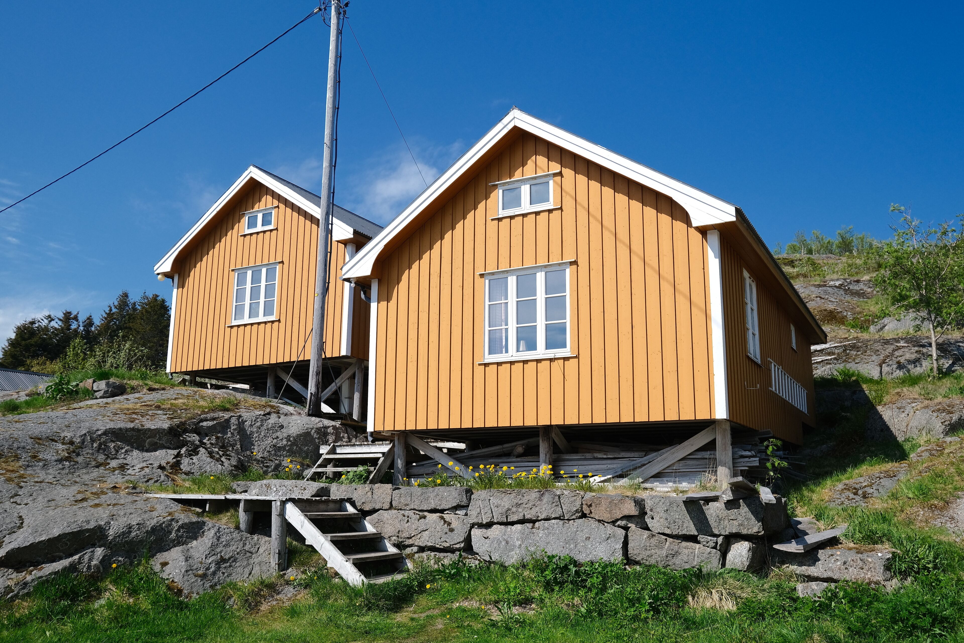 A wooden cabin with a sloped roof, a small porch, and a stone staircase leading up to the entrance.
