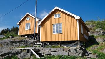 A wooden cabin with a sloped roof, a small porch, and a stone staircase leading up to the entrance.