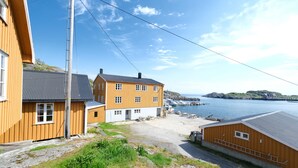 Un bâtiment situé sur la côte, avec un toit gris, un revêtement en bois et une zone aménagée en quai.