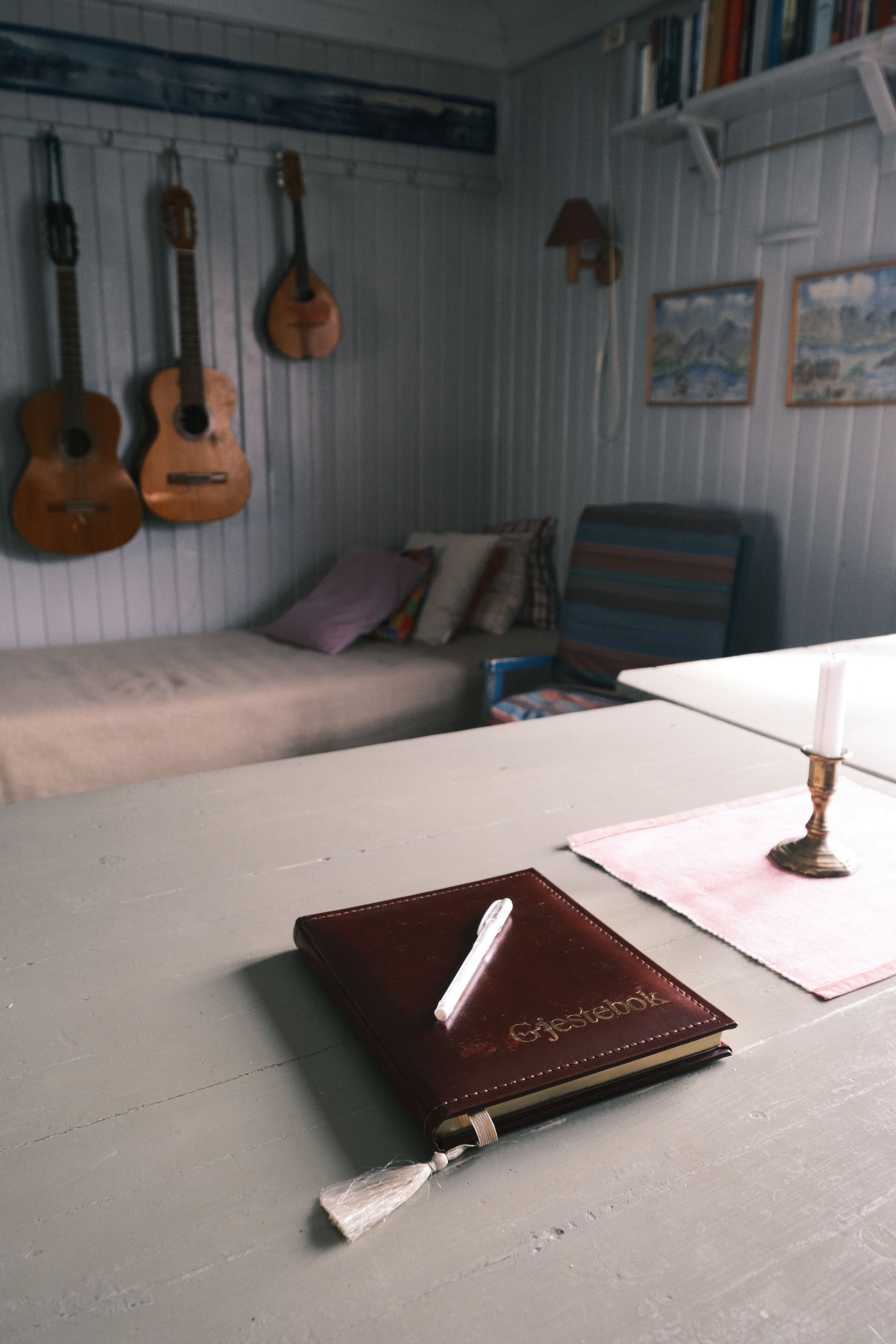 Una habitación con una mesa blanca, un cuaderno de cuero marrón y una lámpara.