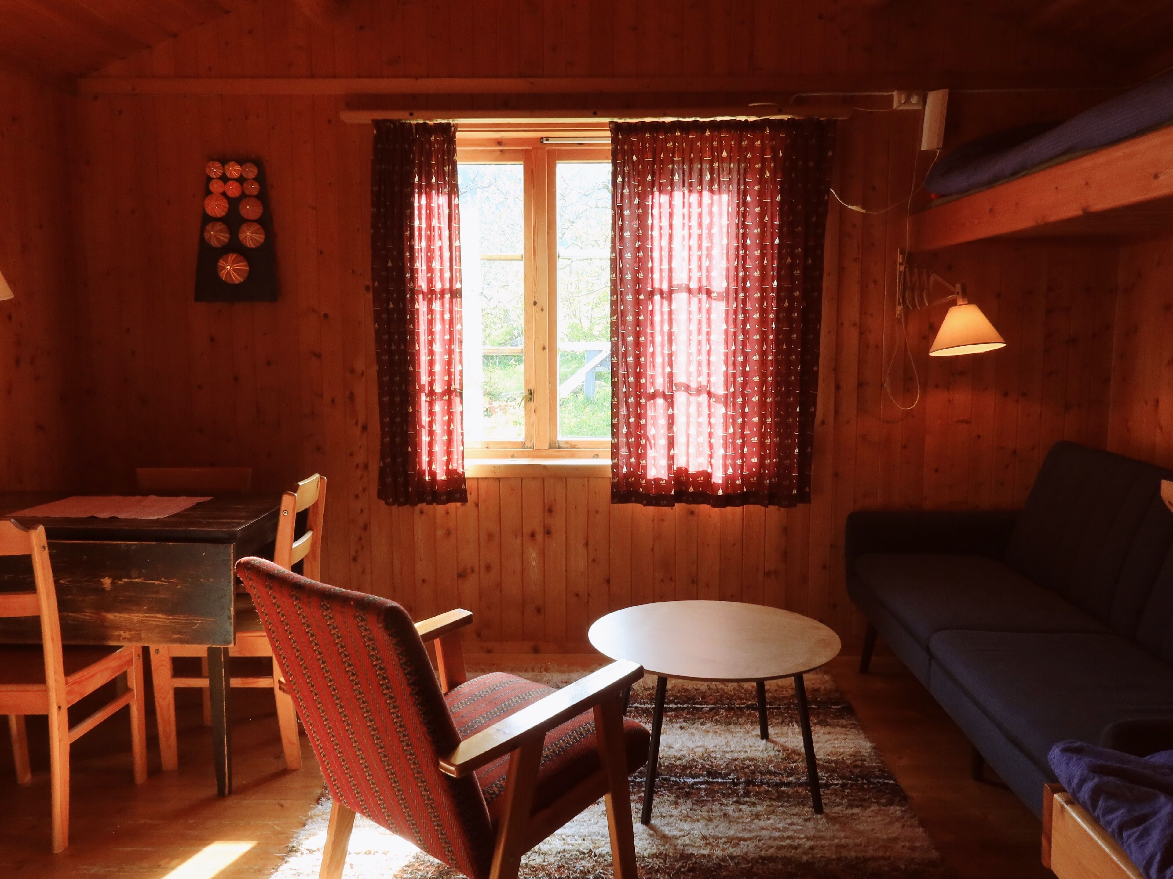 Une pièce chaleureuse avec un décor intérieur en bois, une table à manger avec des chaises, une table ronde et un canapé.