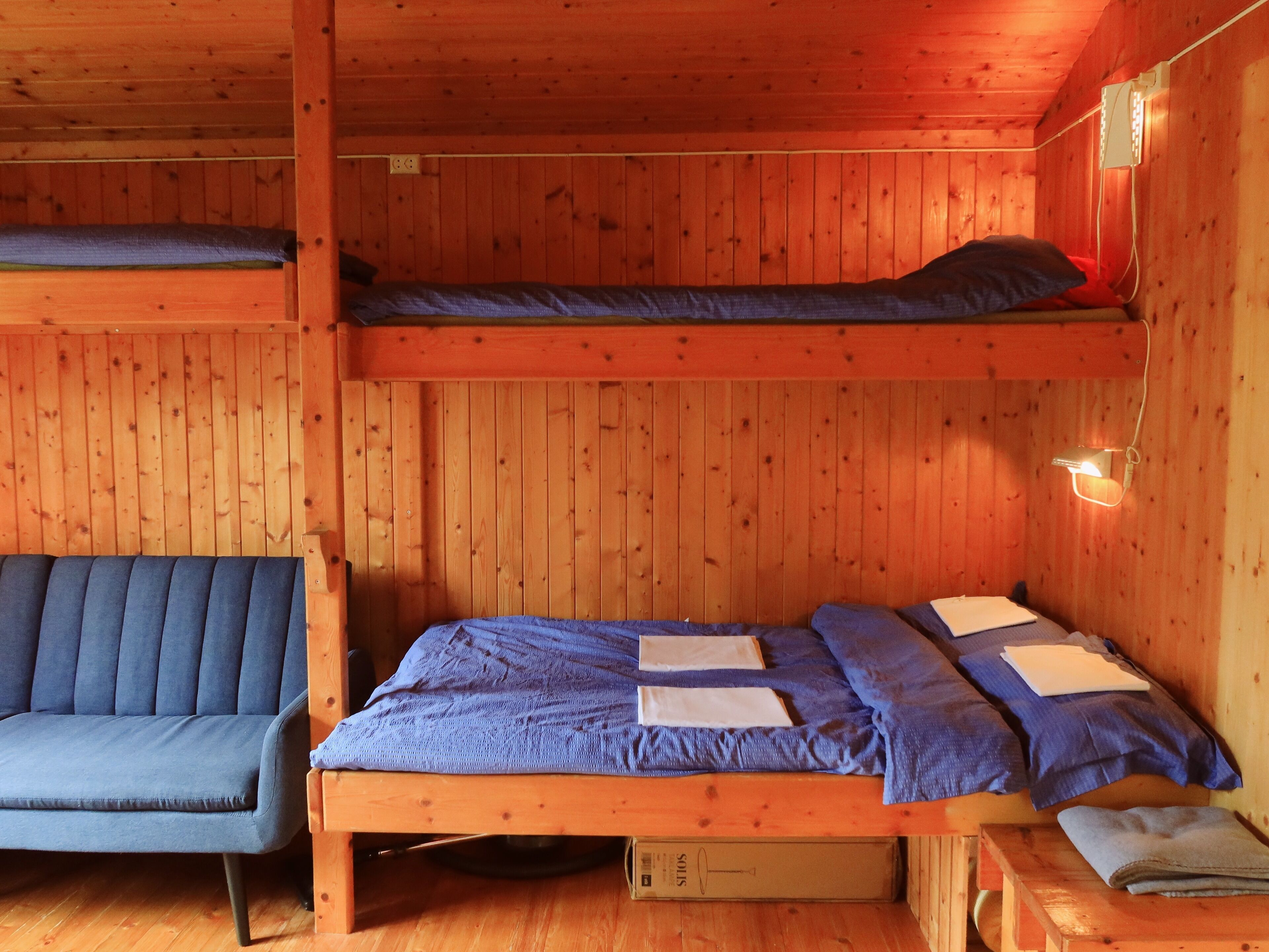 Una cabaña con una cama litera, un sofá y una pequeña mesa.