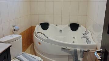 Un baño con bañera, inodoro, lavabo y ventana.
