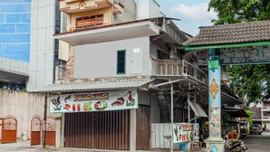 A building with a closed shop front, a balcony, and a staircase leading to an upper floor. - Hotel O Wongso Residence Syariah (Pangkalpinang)